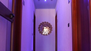 A hallway with a blue carpet, wooden doors, and a decorative mirror on the wall. - Villa Verdesca (San Vito Lo Capo)