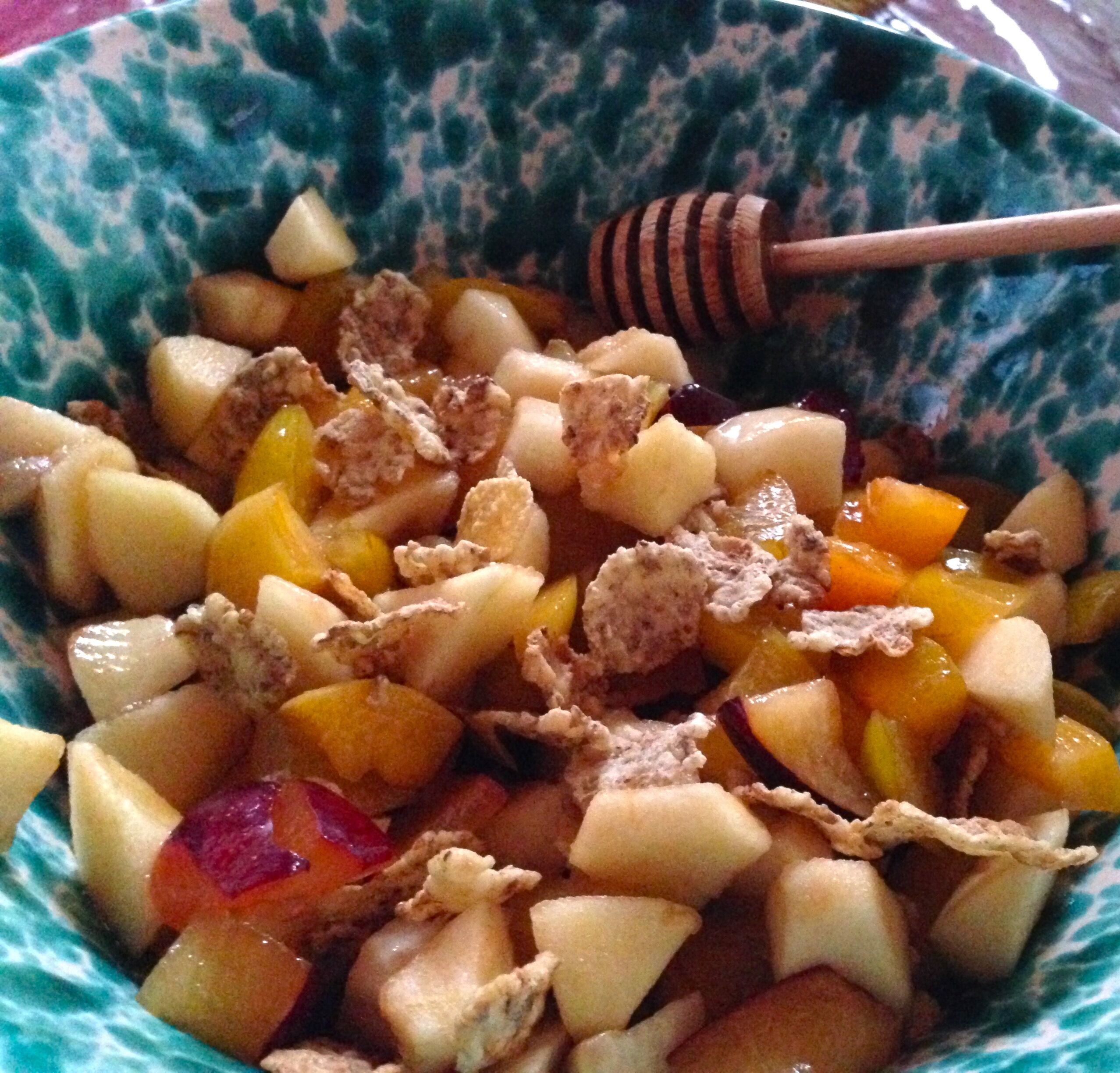 A bowl of fruit salad with various fruits and granola.
