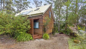 A small wooden cabin with a sloped roof, solar panels, and a small porch.
