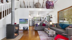 A spacious living area with a fireplace, a sofa, a coffee table, and a kitchen in the background.