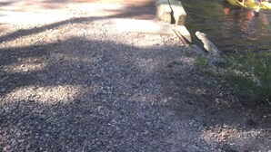A gravel path leading to a bridge over a river, surrounded by trees. - Iconic Red House at red house hole! (Bellvue)