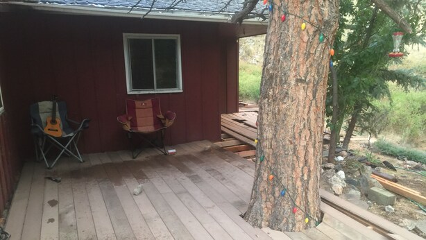A wooden deck with a red building, a guitar, and a folding chair. - Iconic Red House at red house hole! (Bellvue)