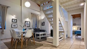 Una sala de estar moderna con comedor, una escalera y un dormitorio.