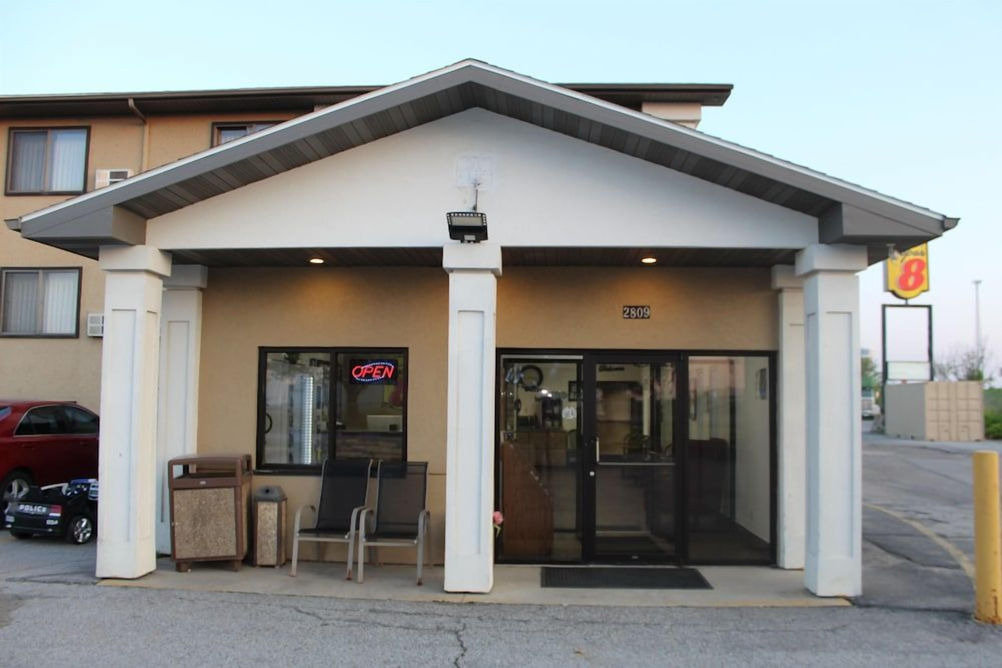 A building with a covered entrance, a sign indicating it's open, and a visible address number.