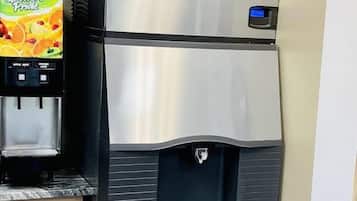 A stainless steel refrigerator with a water dispenser and a small potted plant on top.