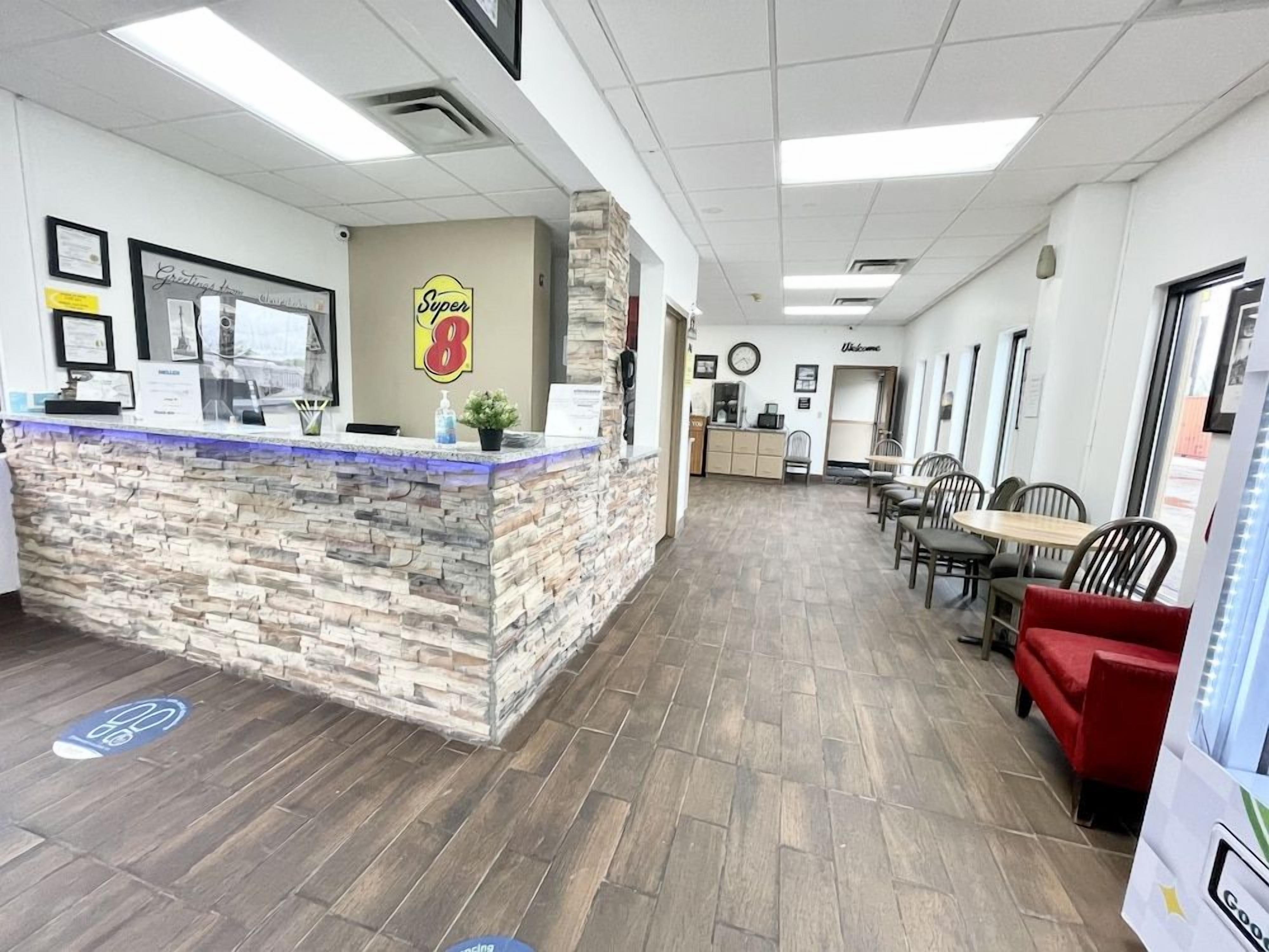 A reception area with a stone counter, framed certificates, and a Super 8 logo.