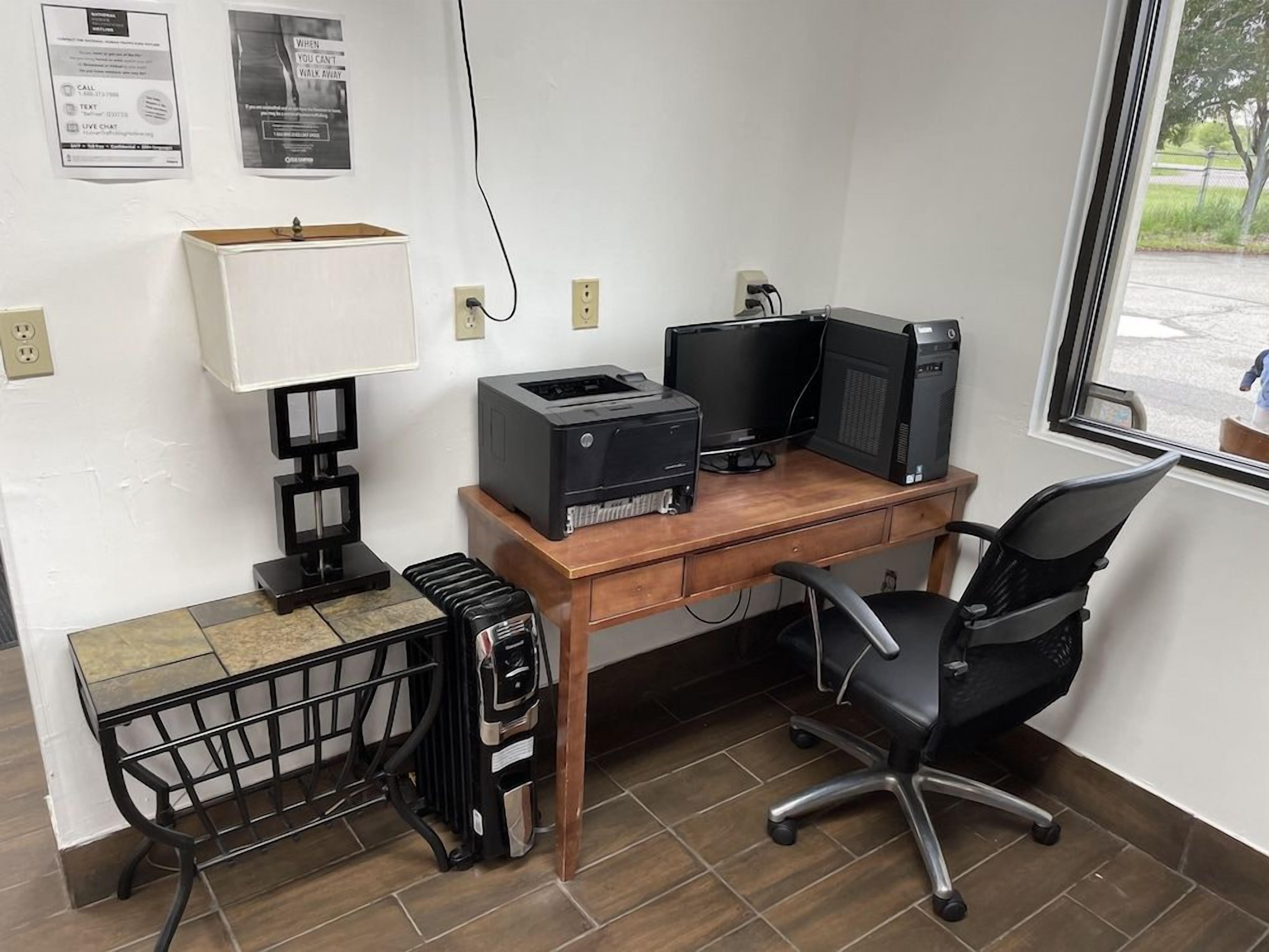 Un espacio de trabajo en casa con escritorio, computadora, impresora y silla.
