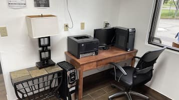 A home office setup with a desk, computer, printer, and chair.