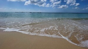 A beach with clear water, a sandy shore, and a partly cloudy sky. - Beautiful One Bedroom Ocean View Gem (Spring Garden)