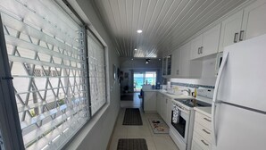 A modern kitchen with white cabinets, a built-in oven, and a refrigerator. - Beautiful One Bedroom Ocean View Gem (Spring Garden)