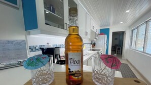 A kitchen area with a wooden cutting board labeled "Freshwater Bay" displaying a bottle of rum punch and two crystal glasses. - Beautiful One Bedroom Ocean View Gem (Spring Garden)