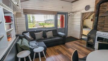 Un cuarto acogedor con sofá, dos taburetes, una mesa, chimenea y vistas al exterior.
