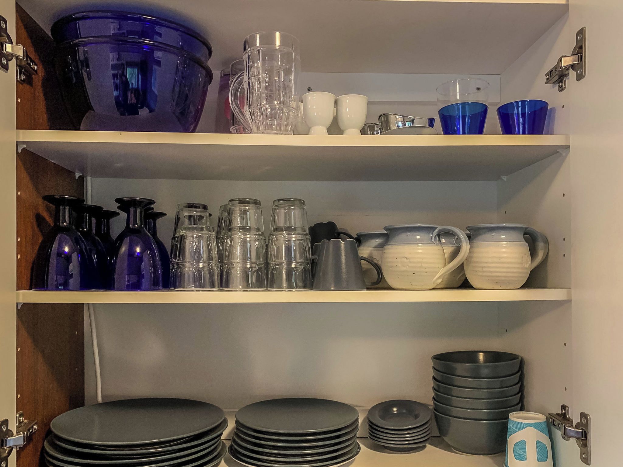A kitchen shelf with various glassware and dishes.