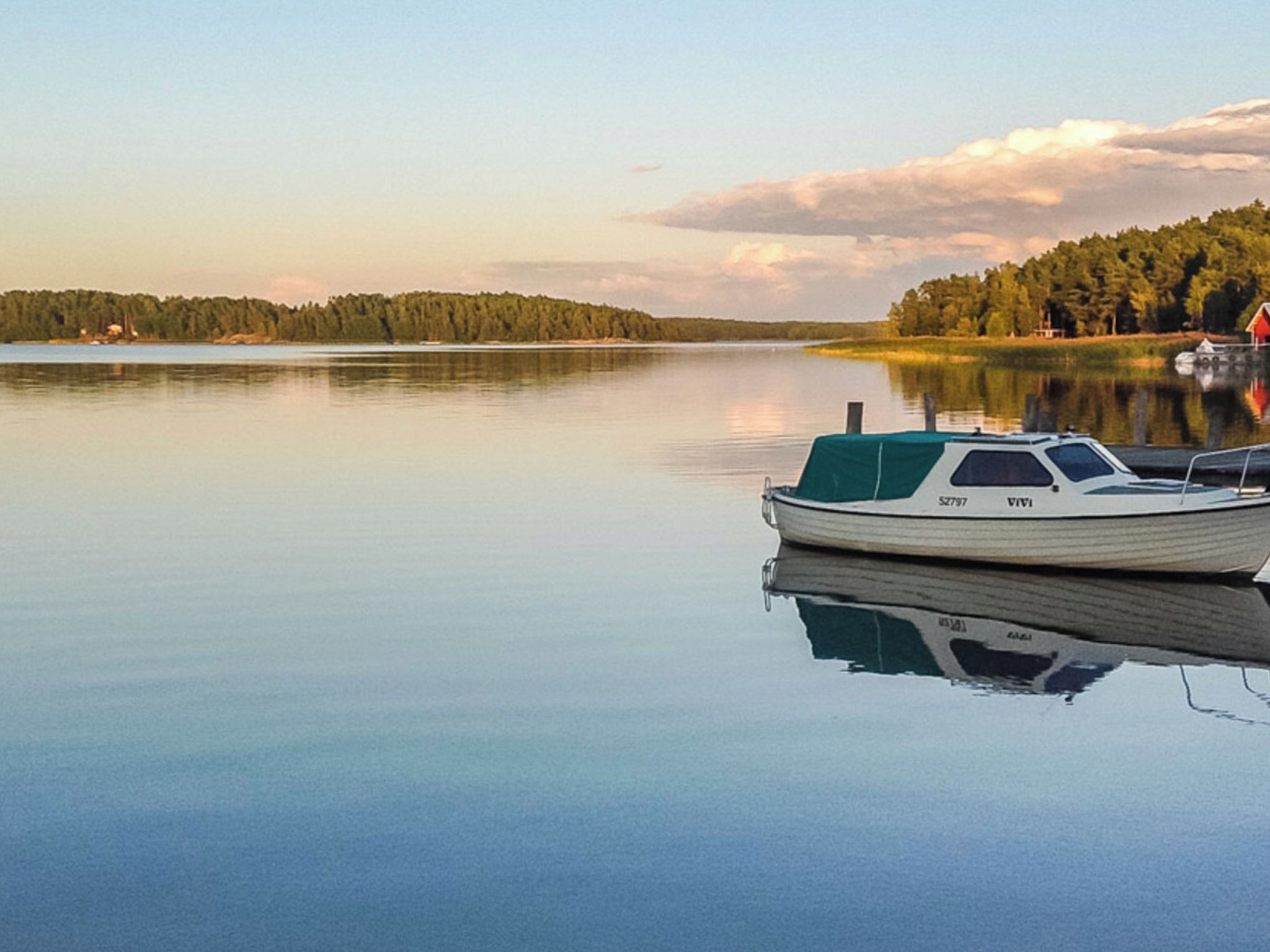 A calm lake with a boat docked on the right side.