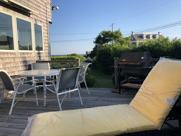 Un patio con mesa y sillas, una parrilla y una silla de descanso cubierta.