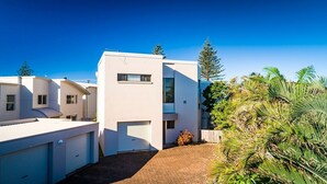A modern residential building with a flat roof, large windows, and a paved driveway. - Ocean Waves - Downtown Oceanfront (Lennox Head)