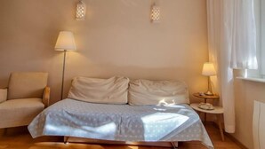 A bedroom with a bed, two bedside tables, a chair, and two wall-mounted lamps.
