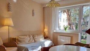 A cozy room with a bed, a round table, and chairs. There is a window with a view of trees and buildings outside.