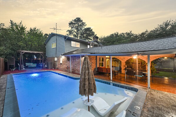 A backyard with a swimming pool, lounge chairs, and a covered patio area. - Private Retreat w/ Pool, Patio, BBQ! 6BR 3BA Gem (Houston)