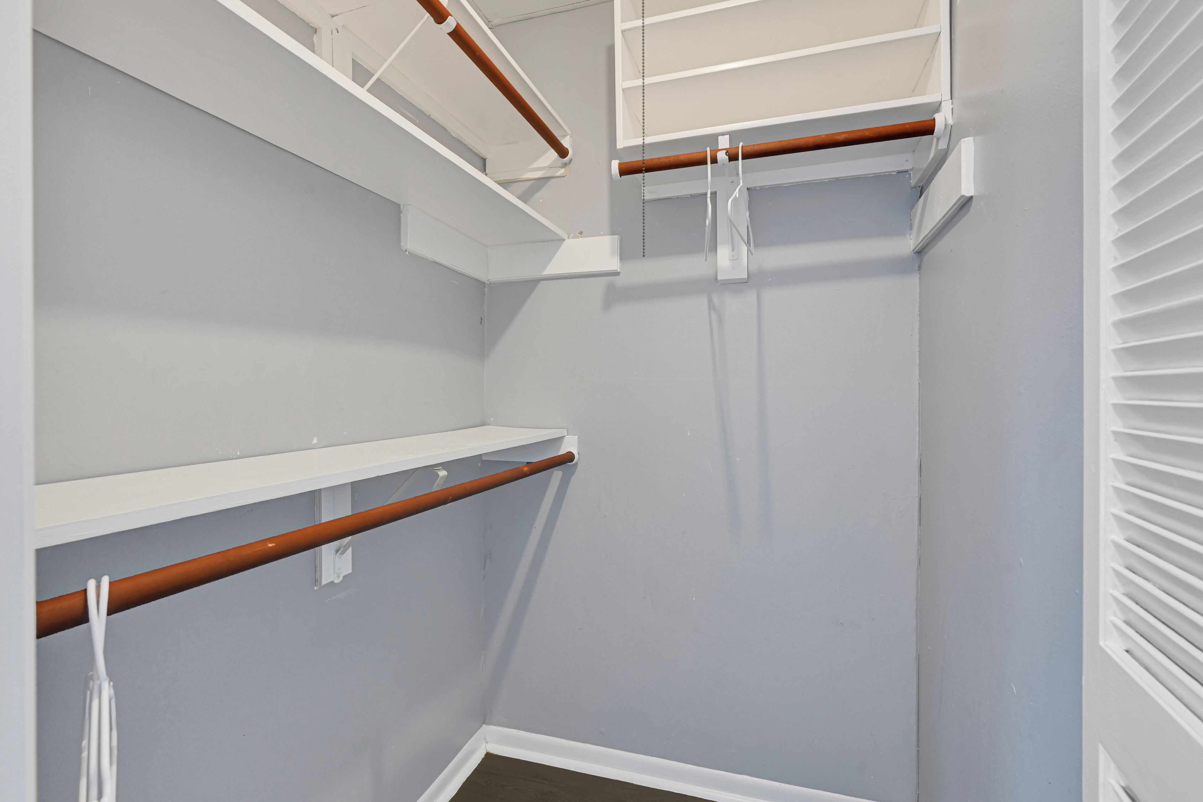 A corner of a room with white walls, a wooden beam, and a white shelf.
