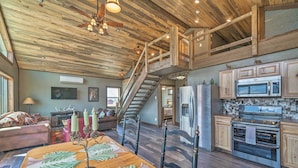 A spacious living area with a wooden ceiling, a staircase, a kitchen with modern appliances, and a cozy seating area. - Day Trip to Yellowstone NP! Mtn-View Cabin (Livingston)