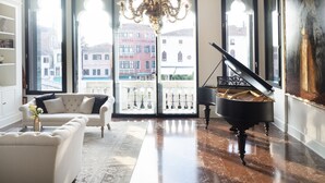 A spacious living room with a grand piano, a white sofa, and a chandelier. - Palazzetto Foscari (Venice)