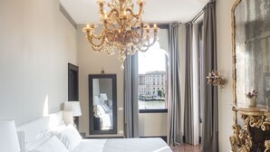 A hotel room with a large bed, a chandelier, a mirror, and a view of the city through the window. - Palazzetto Foscari (Venice)