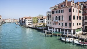 A canal with buildings on one side and boats docked along the water. - Palazzetto Foscari (Venice)