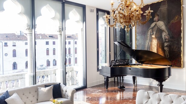 A grand piano in a spacious living room with a large window overlooking a cityscape. - Palazzetto Foscari (Venice)