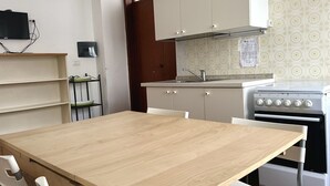 Una cocina con una mesa de madera, armarios blancos, una estufa y un ventanal.