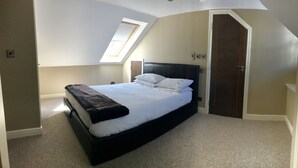 A bedroom with a bed, a skylight, a door, and a carpeted floor. - No14 in the heart of St Andrews (St Andrews)