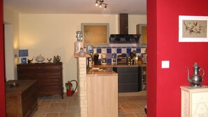 Een keuken met een centraal eiland, een kookplaat en een spoelbak. Er staat een brandblusser op de vloer.