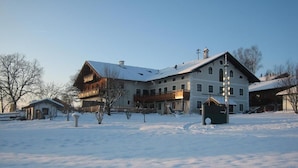 A large building with multiple floors and a sloped roof, surrounded by snow. - Apartment 11 with balcony and terrace, 30 m² (Soyen)