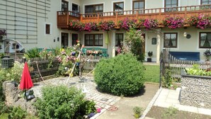 A courtyard with a wooden fence, potted plants, and a red umbrella. - Apartment 11 with balcony and terrace, 30 m² (Soyen)