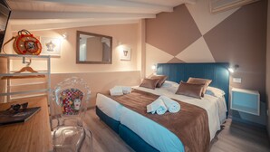 A hotel room with a bed, a desk, a chair, a mirror, and a wall-mounted TV. - A' Coffa (Taormina)