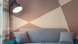 A modern living room with a sofa, pillows, and a floor lamp. - A' Coffa (Taormina)