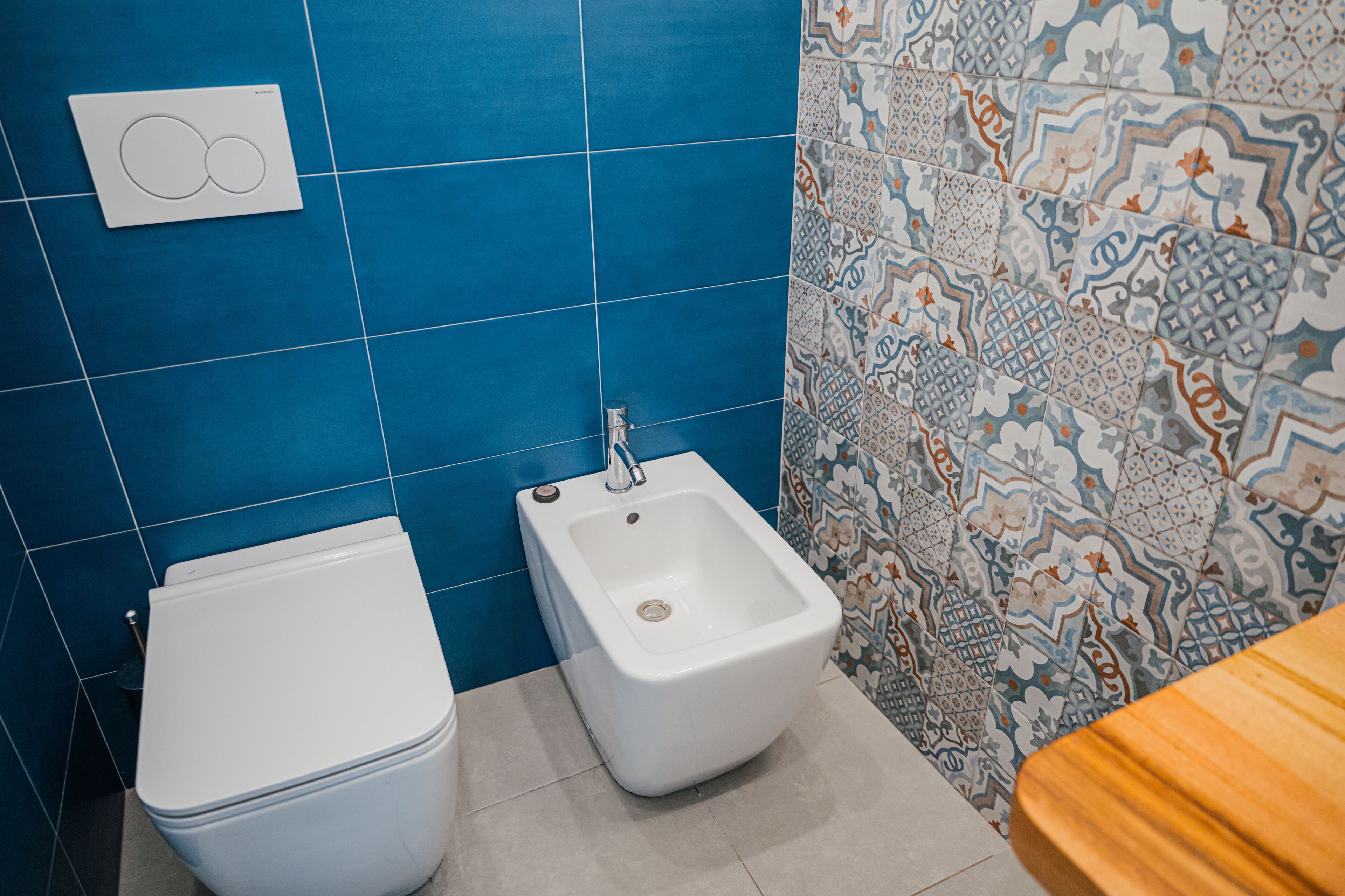 Ein Badezimmer mit Toilette, Bidet und Fliesen mit Muster.