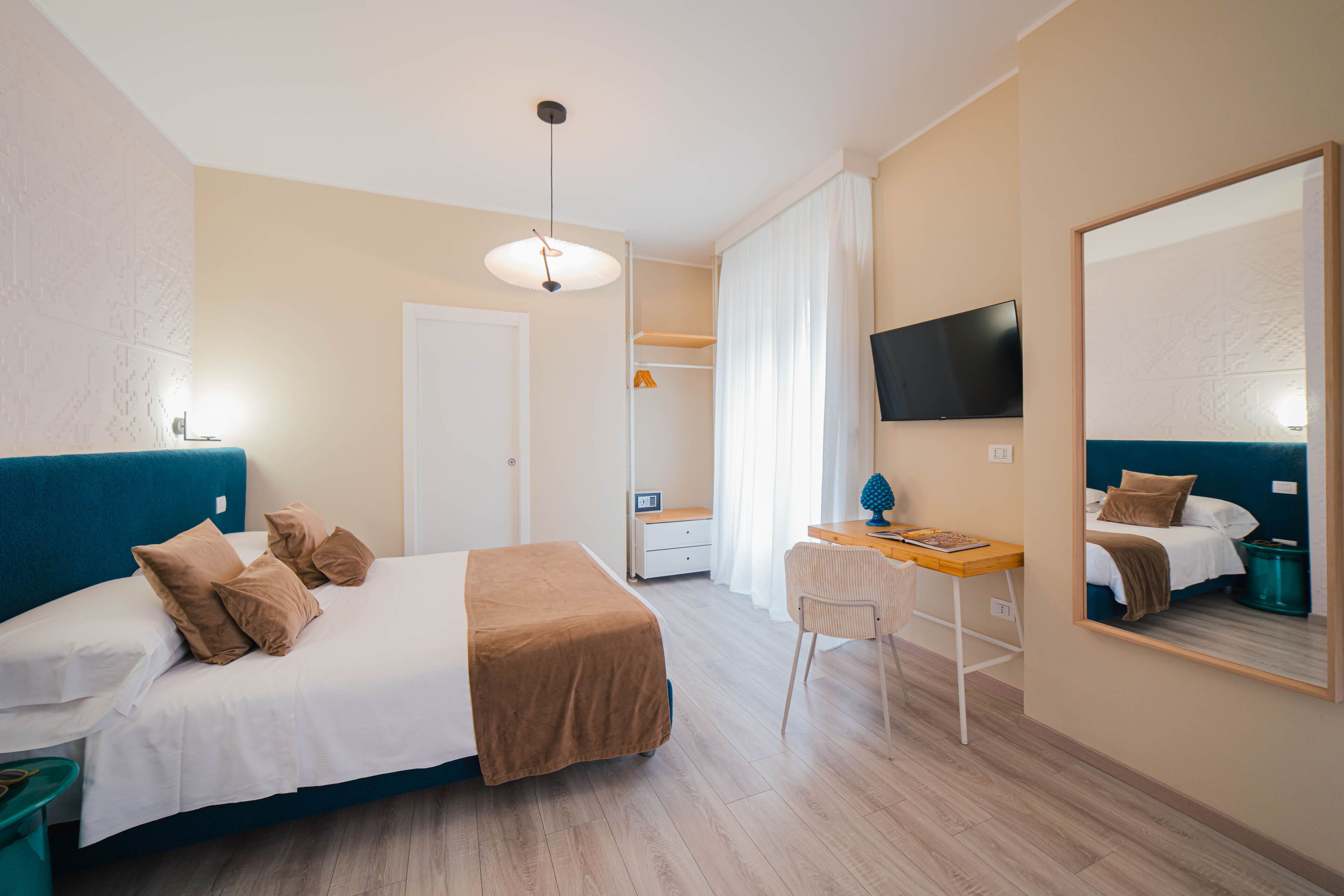 A bedroom with a bed, desk, chair, and a TV.