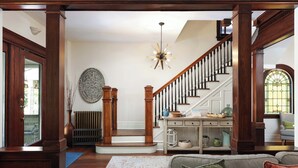 A spacious living area with a wooden staircase, a large decorative mirror, and a cozy seating area.