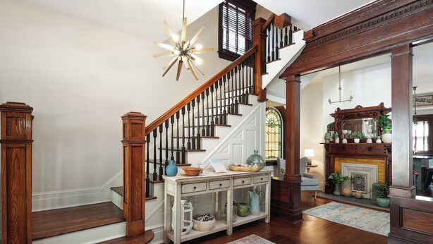 A grand staircase with wooden railings and a console table with decorative items.