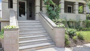 A two-story building with a front entrance, a set of concrete stairs, and a small porch area.