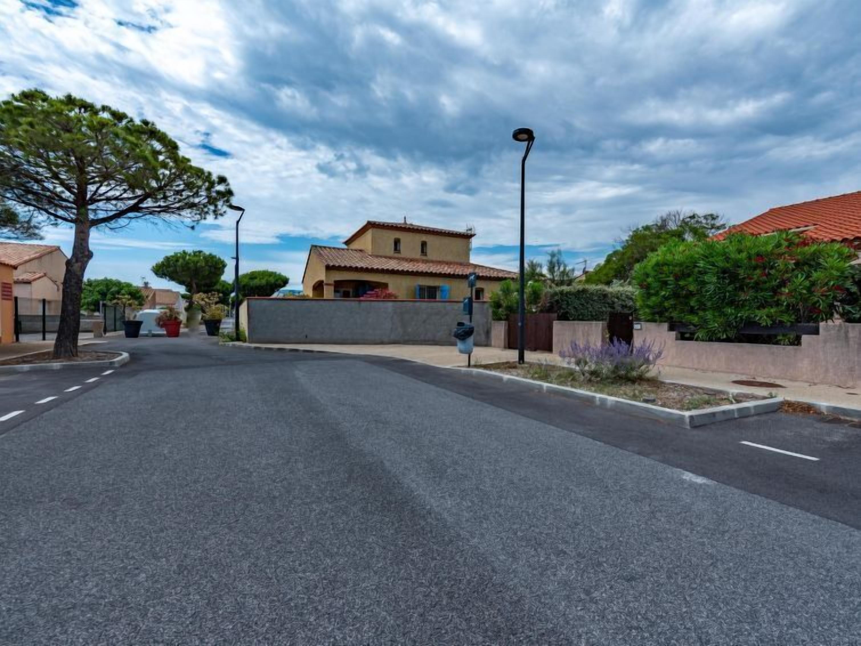Una calle tranquila con una casa de dos pisos, un farol y un cielo despejado.