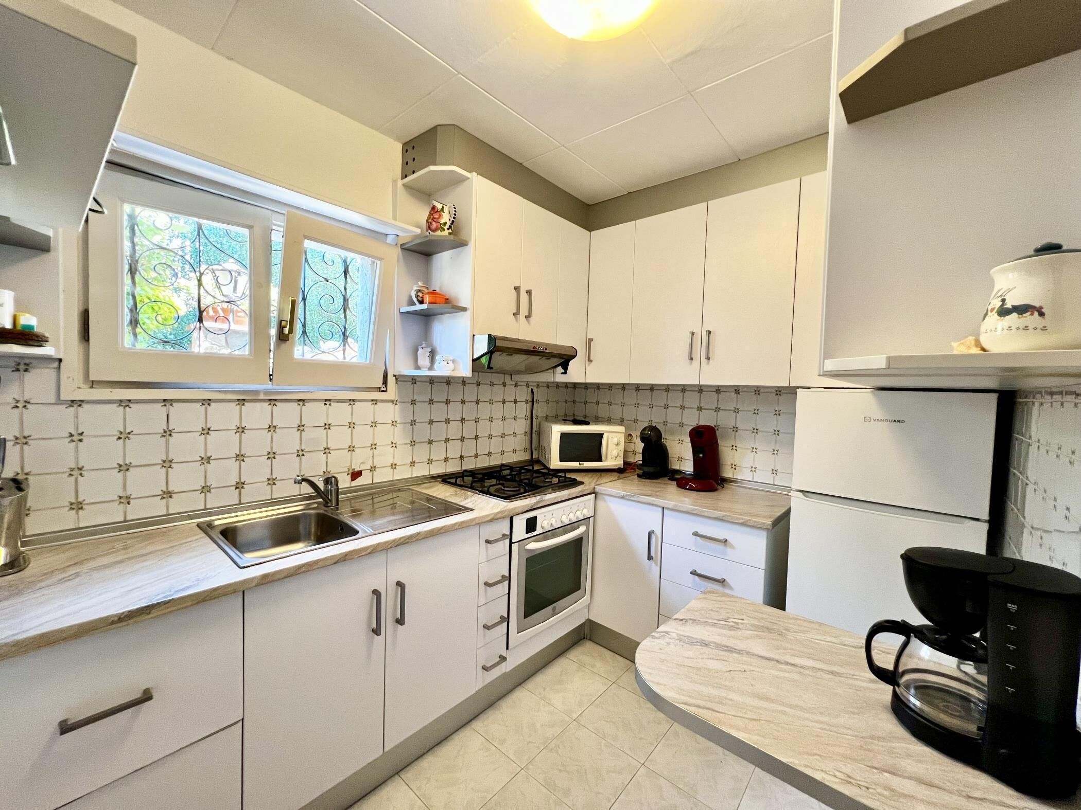 A kitchen with white cabinets, a stove, a microwave, and a coffee maker.