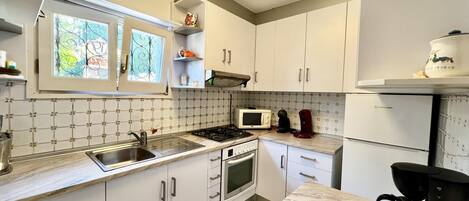 A kitchen with white cabinets, a stove, a microwave, and a coffee maker.