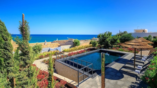 A pool area with a view of the sea, surrounded by greenery and a small gazebo. - Casa Magnolia - Luxury villa with private heated pool and sea views! (Carvoeiro)