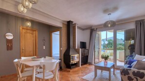 A modern living room with a fireplace, a dining area with a table and chairs, and a sofa with a cow print cushion. - La Felicidad by Interhome (Dénia)