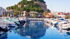 A marina with boats docked, a clear sky, and a hill with buildings and greenery in the background. - La Felicidad by Interhome (Dénia)