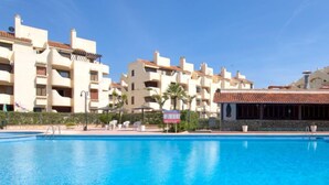 A swimming pool with adjacent multi-story buildings, some with balconies and a covered area with umbrellas. - La Felicidad by Interhome (Dénia)