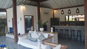Una sala acogedora con un sofá, taburetes de bar, un televisor y una planta grande en maceta.
