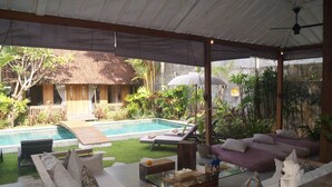 Un espacio al aire libre cubierto con piscina, sillas de descanso y una mesa de comedor.